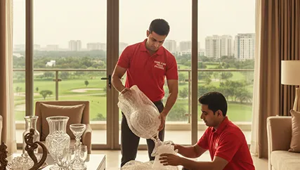 Movers carefully wrapping fragile items for relocation in Golf Course Extension