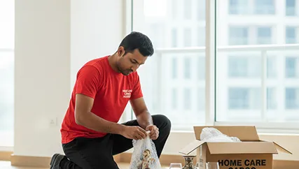 Movers wrapping fragile glassware in protective material in Sector 16, Gurugram