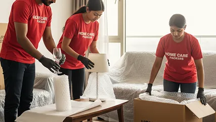 Movers wrapping fragile items and securely packing them into boxes