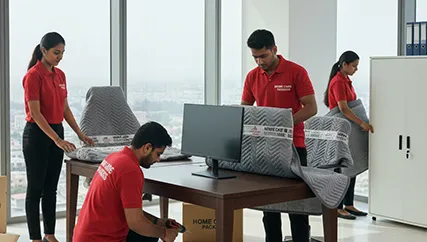 Office movers disassembling office furniture and carefully packing electronics in Sector 74