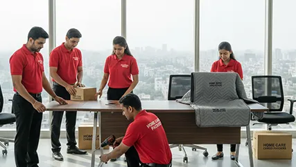 Office movers carefully disassembling furniture and packing office electronics in Sector 91