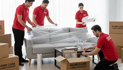 Movers carefully packing living room furniture and fragile items like vases and artwork