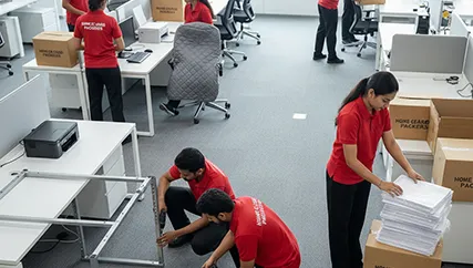 Movers disassembling office furniture and packing electronics in a corporate office in Muhana Mandi