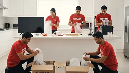 Movers packing kitchen items, fragile items, and electronics in a home