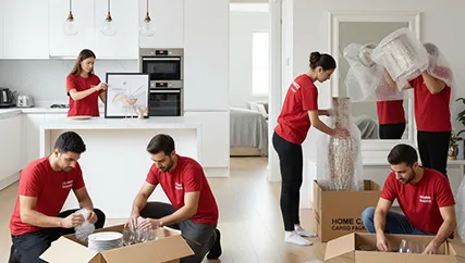 Movers packing delicate glassware and kitchenware into protective boxes