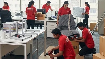 Office movers organizing and packing computers, desks, and office chairs in a workspace