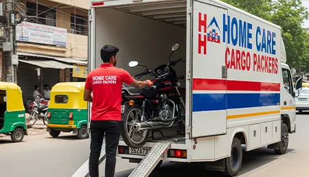 Professional mover carefully loading a motorcycle onto a secure transport vehicle in India