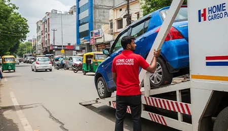 Mover loading a car onto a specialized carrier vehicle for transport, in an urban Indian setting